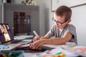 boy working on school work while video conferencing